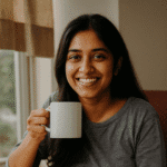 Young Indian woman sitting by a window, sipping tea and journaling peacefully, reflecting mindfulness and intentional daily routines